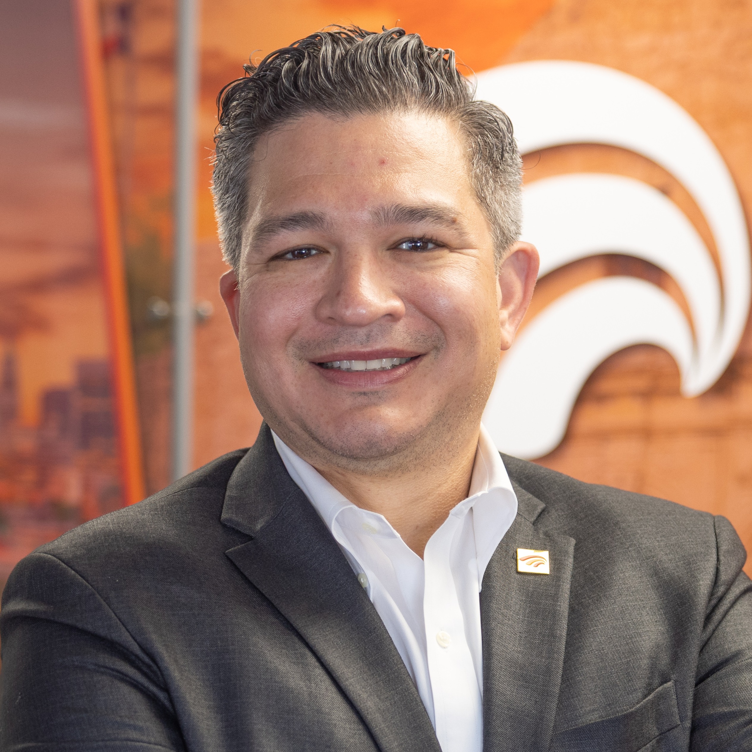 Luis Rodriguez in a grey suit and white shirt smiling at the camera.