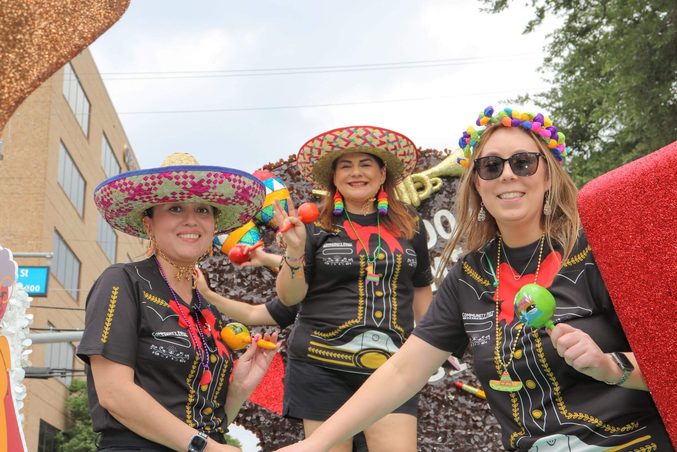 Three happy women in Mariachi-style shirts and sombreros participate in Battle of the Flowers Parade.