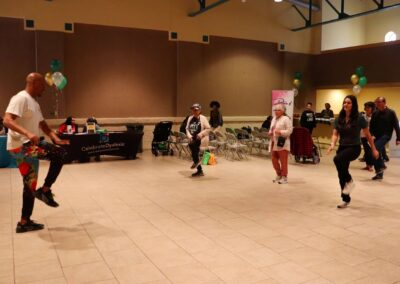 People participate in a dance exercise class near a "Celebrate Dyslexia" table.