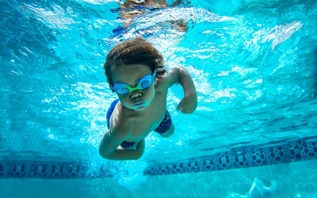 Young boy swimming underwater with goggles