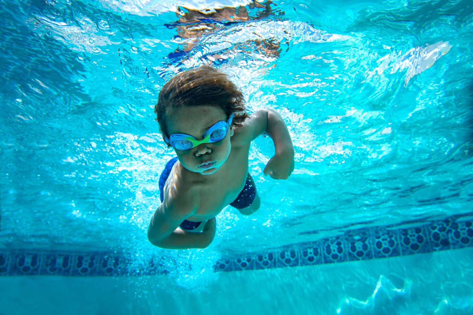 Young boy swimming underwater with goggles
